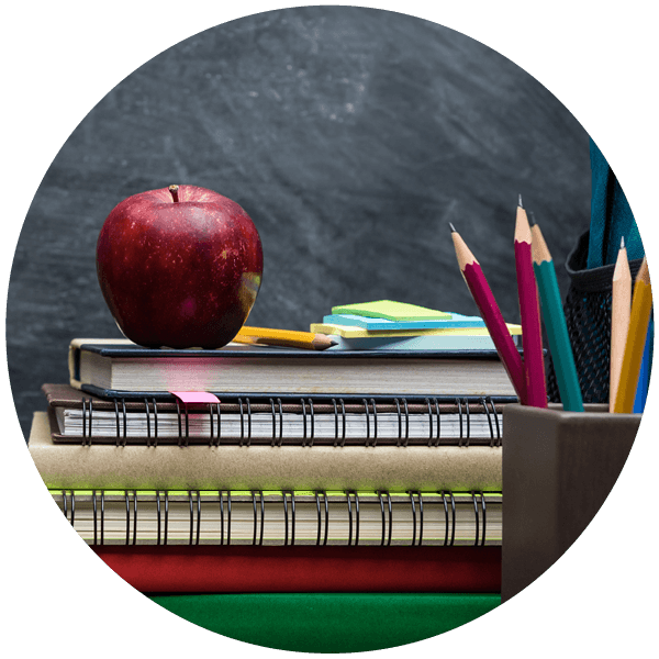A stack of notebooks on a desk in a classroom.