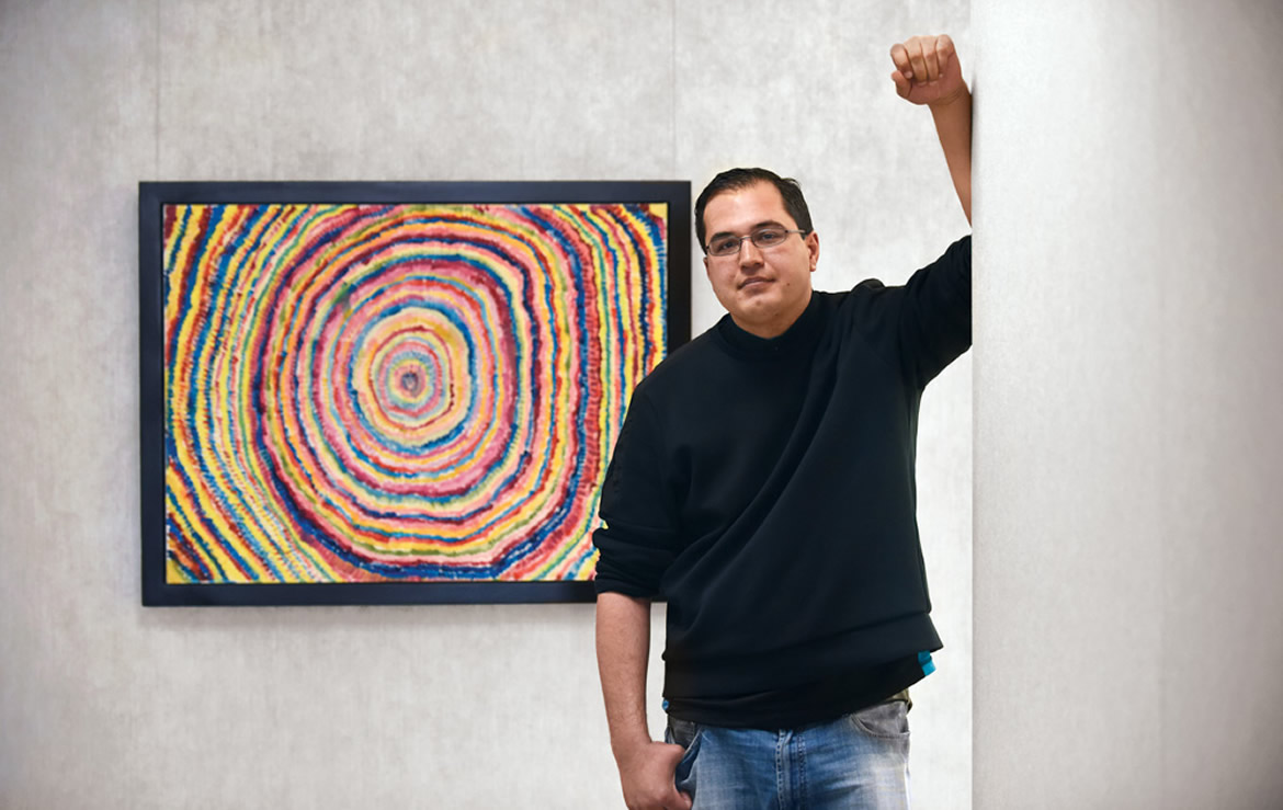A photo of Travis with some of his art.