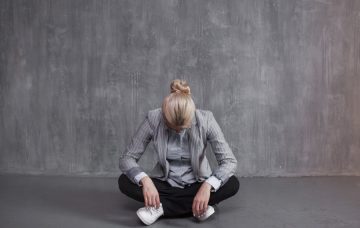 A woman lowers her head in an empty room.